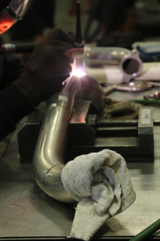 The far end of this header tube has the plug with the argon filler tube; the near end has the rag stuffed inside to keep the argon from leaking out while the welding process is underway.